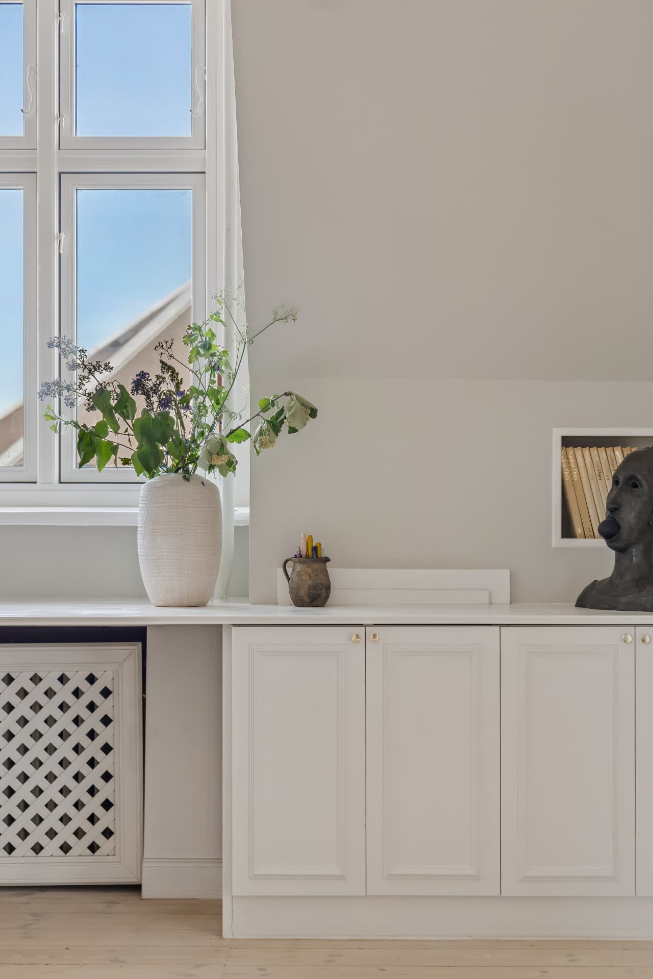 Vase med sommerblomster ved hvidt vindue i klassisk lejlighed